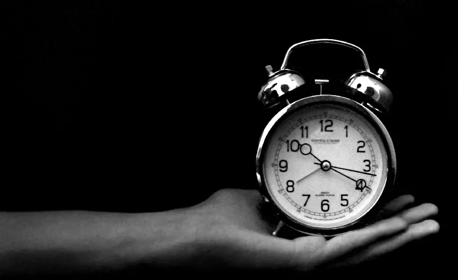 Download a black and white conceptual image of a clock with an old bell on the hand