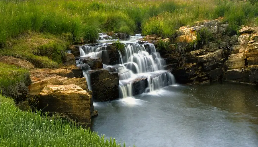 Download Background Beautiful small stepped waterfall in the heart of green nature