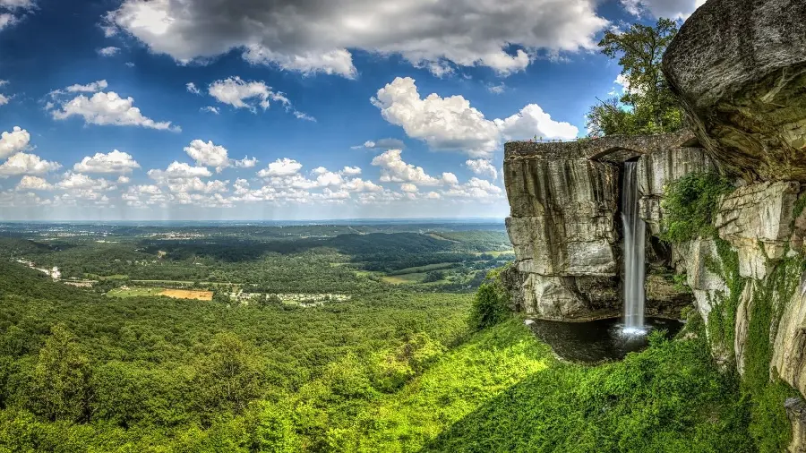 A masterpiece of nature wallpaper of a tall waterfall over a vast green plain