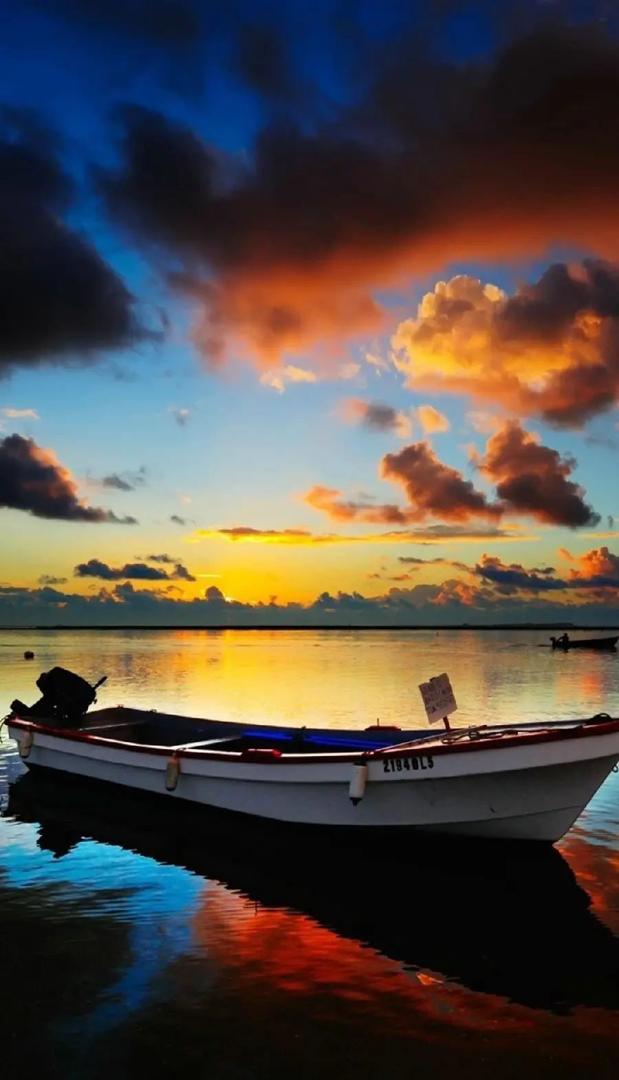 Free and luxurious wallpaper of a boat in a spectacular sunset for mobile