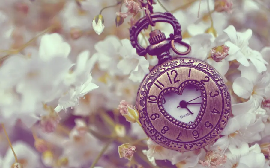 Amazing and spring image of a heart-shaped pendant clock among beautiful blossoms