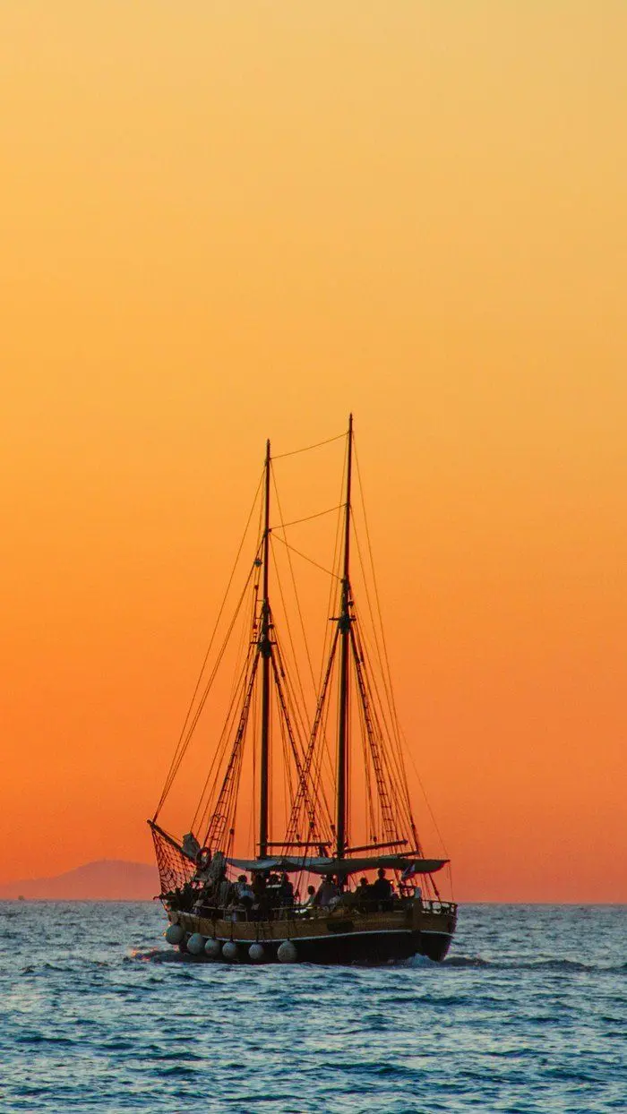Download Wallpaper Of A Beautiful Boat On The Blue Sea And Under The Orange Sky