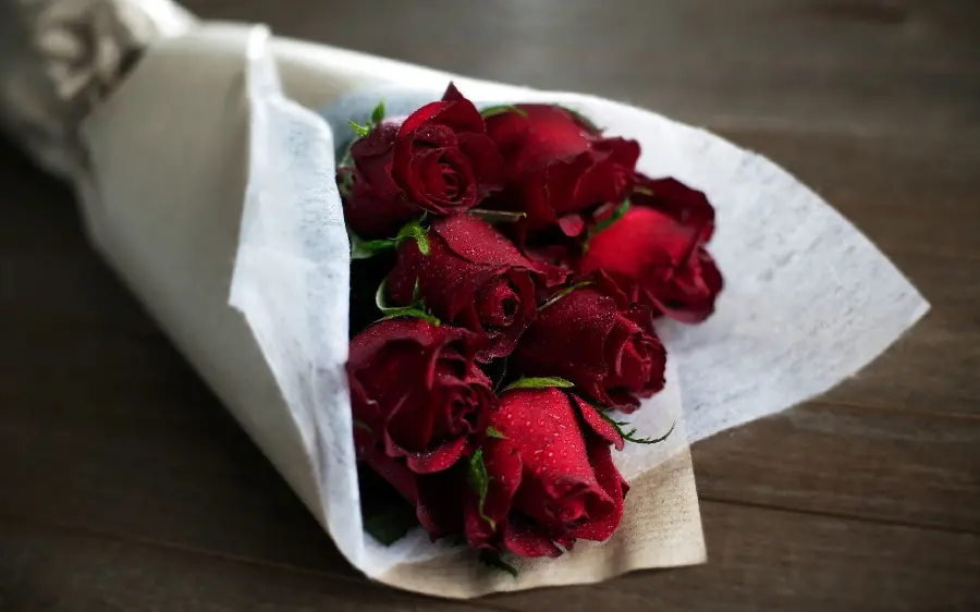 Dreamy image of a simple red rose bouquet with white paper