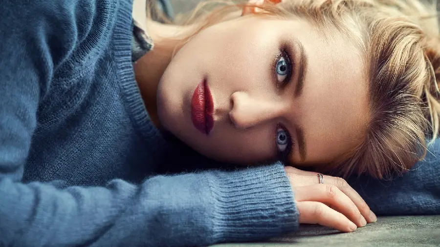 Photo of a beautiful girl with colored eyes lying on the ground with a lovely look