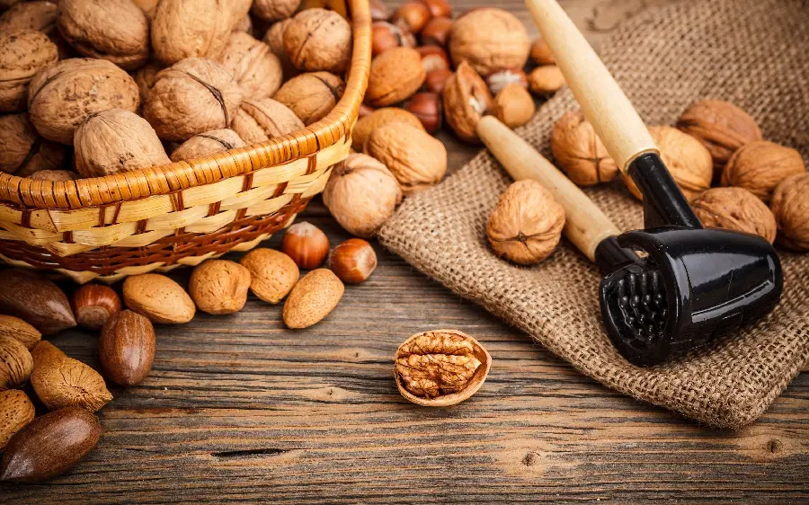Photo of various walnuts and almonds next to a walnut crusher