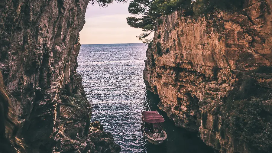 Artistic post of a small boat between two rocks in the sea for instagram