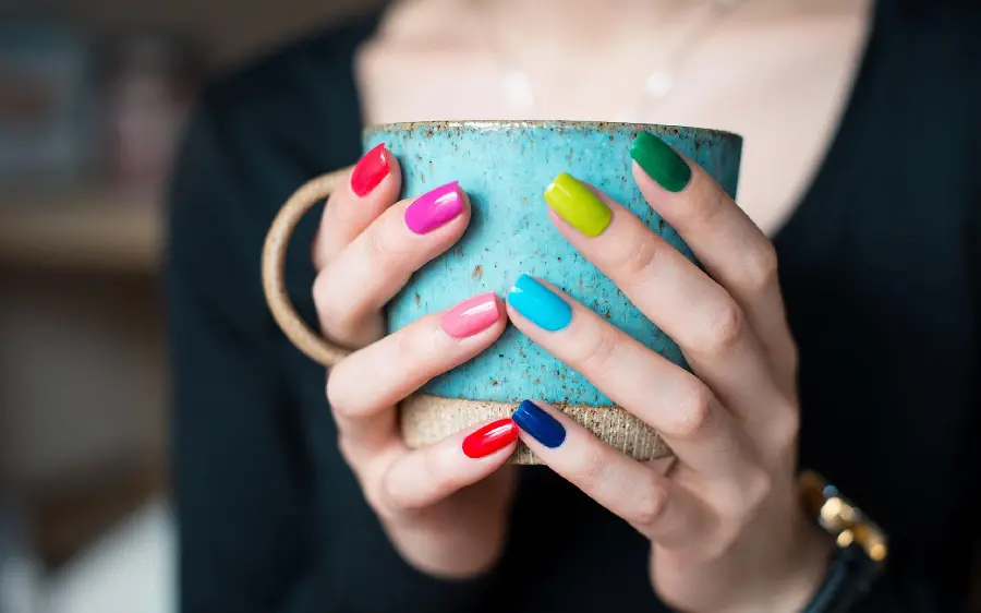 Profile photo of a cup in the hand of a girl with beautiful colored nails 