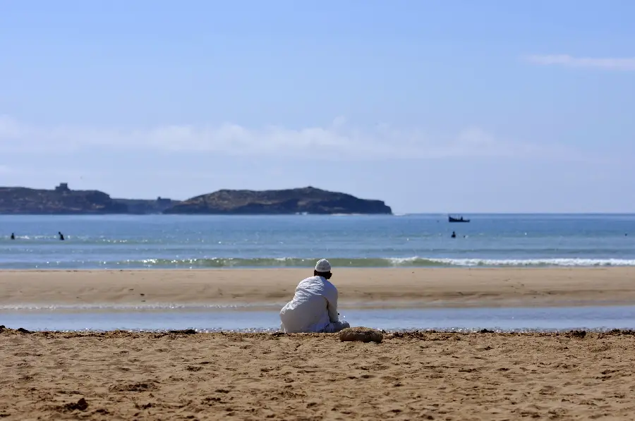 Image of a Moroccan man sitting on the beach watching the sea