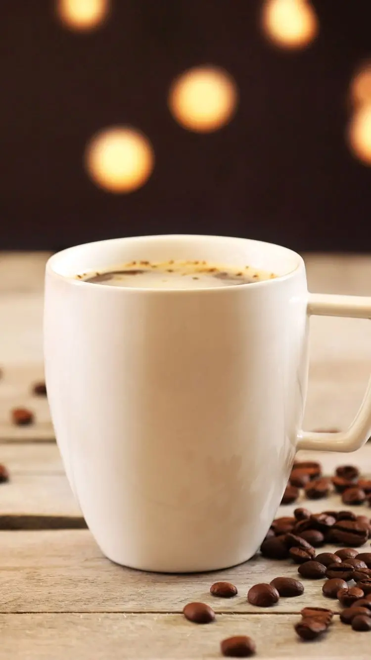 White coffee cup image from the side near natural coffee beans
