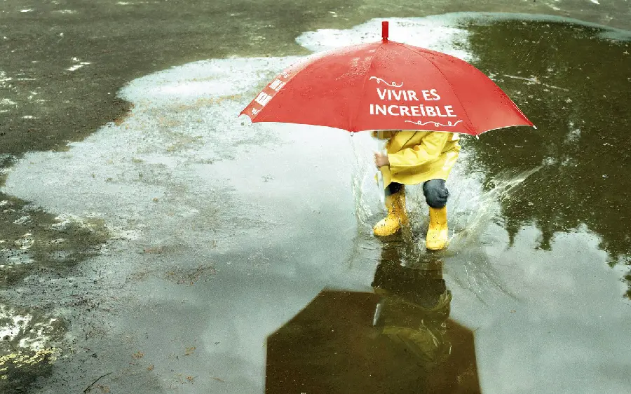 Emotional profile photo of a child in the rain with the Spanish caption vivir es increible or life is incredible