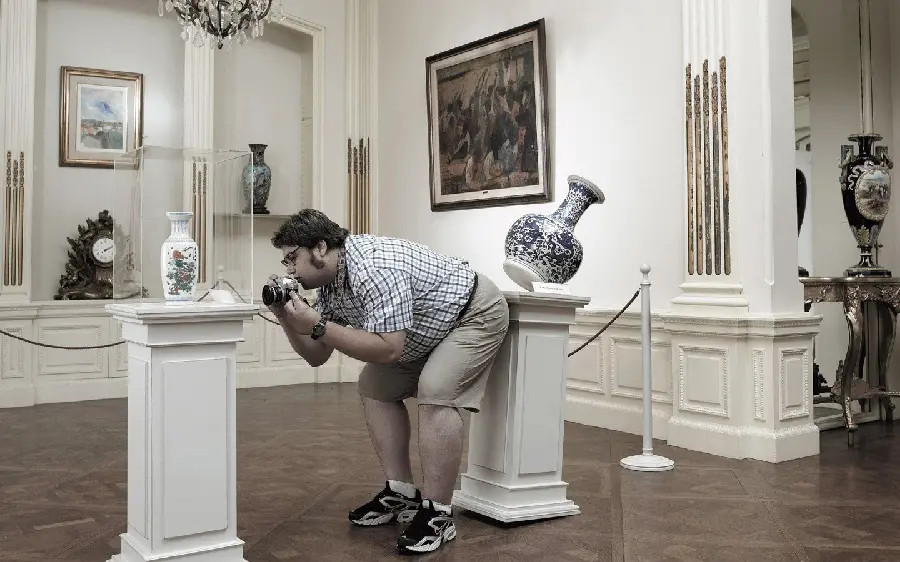 Interesting and funny photo of a fat photographer in a museum wearing shorts
