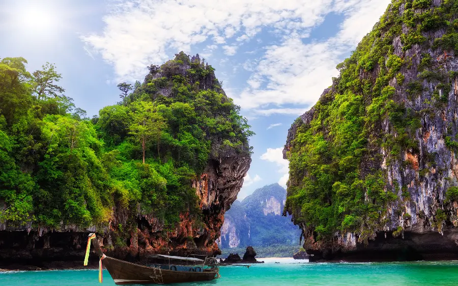 Photo of a boat on the blue sea shore between two rocky cliffs