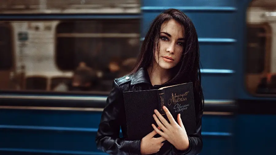 Photo of Black Haired Girl Holding Book in Hand with Penetrating Eyes