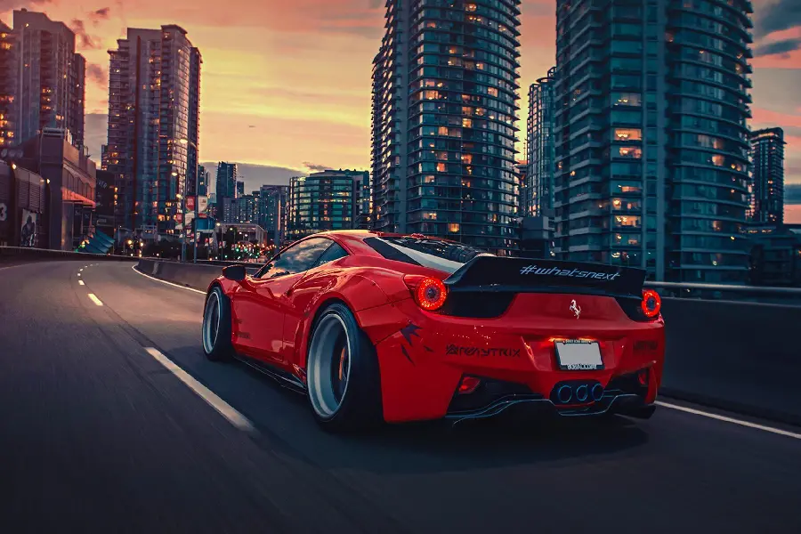 Interesting and spectacular photo of a red car on the road with tall buildings on the side of the road