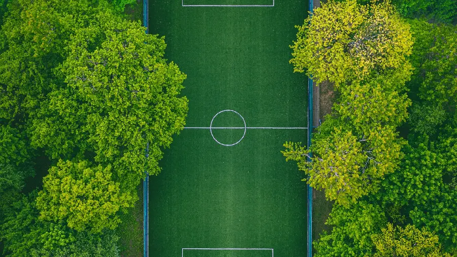 Boyish background of a football field among dense trees
