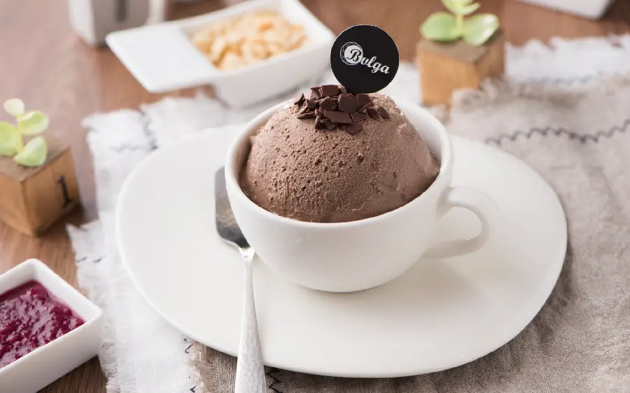Stylish background of a white cup and saucer with chocolate ice cream