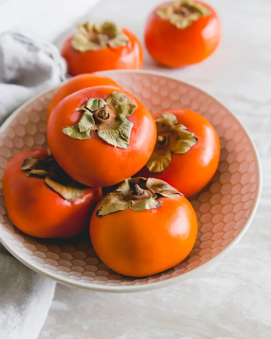 A charming and spectacular picture of delicious persimmons in a patterned bowl