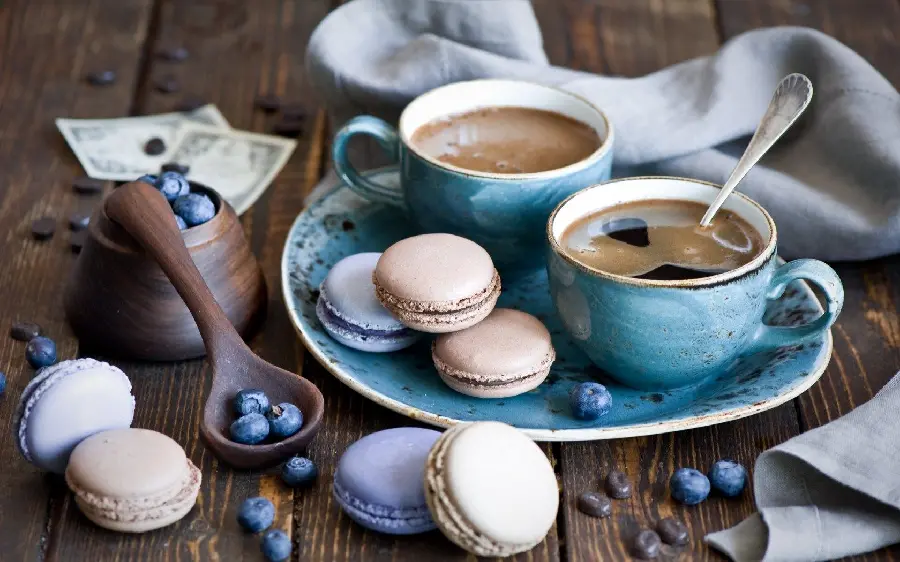 Beautiful background of coffee and blueberry-flavored macarons 