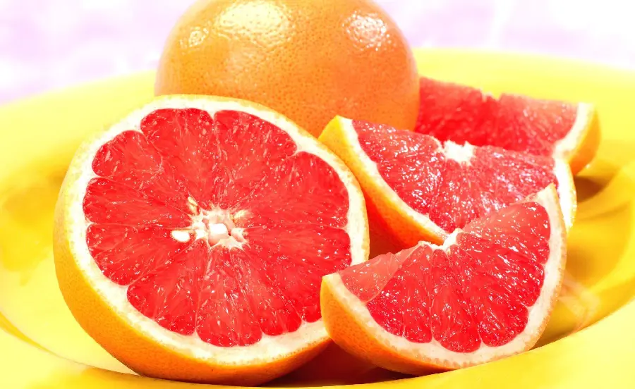 Background of juicy and colorful grapefruit in a yellow bowl