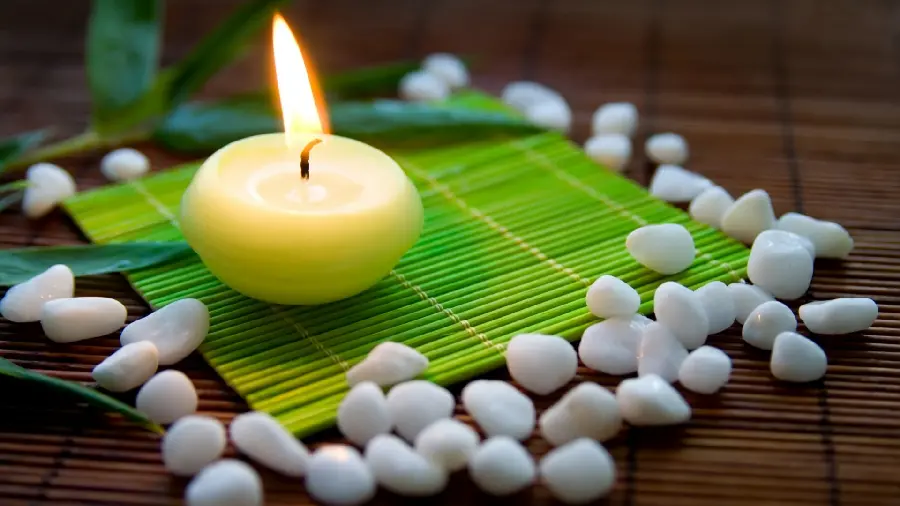 High quality background photo of a white round candle next to a white pebble