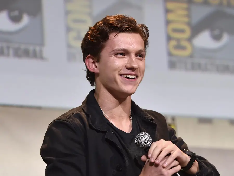 Download a photo of Tom Holland, the famous English actor, holding a microphone 