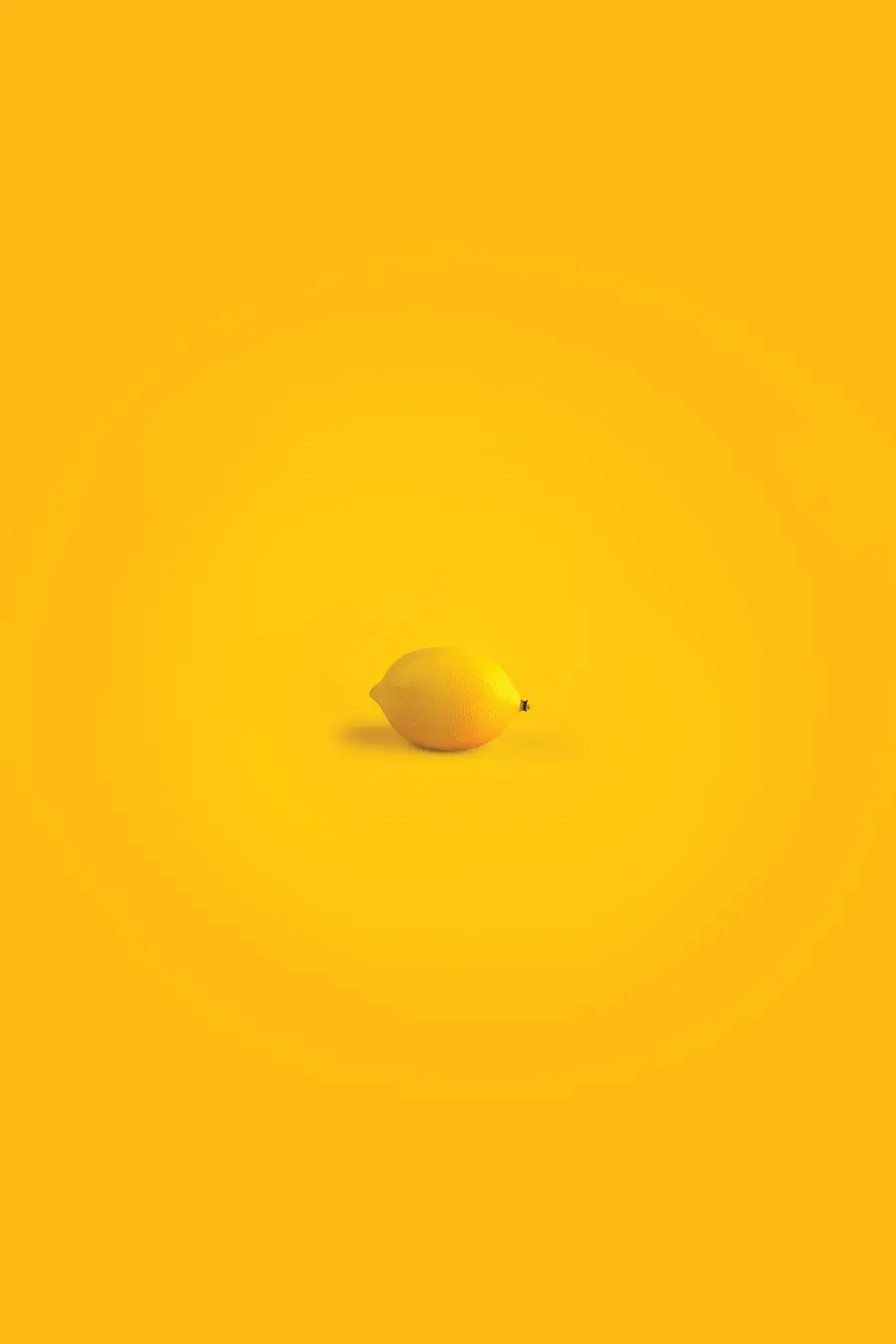 Stock photo of a yellow background with a single lemon in the middle