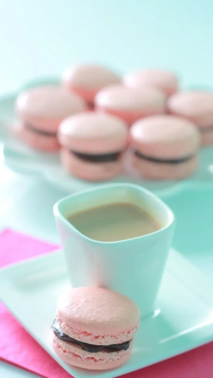 Amazing wallpaper of pink macaroons with coffee next to them 