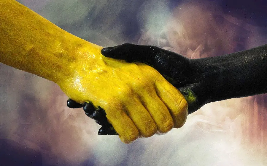 Artistic image of shaking hands of yellow and black with a colored background 
