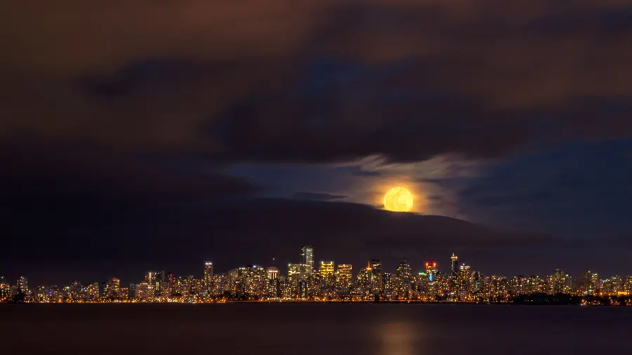 Download a photo of a yellow moon at night, a busy city, in high quality and completely free