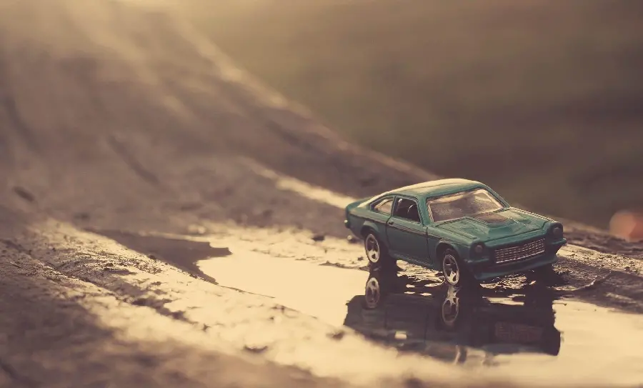 Download a profile photo of a miniature car on a rainy road with a simple background