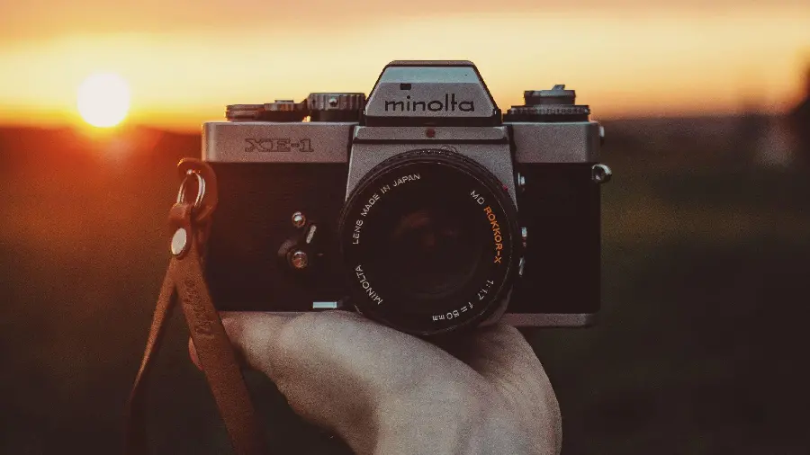 Simple photo of a hand with a camera with a sunset background suitable for photographers' backgrounds 