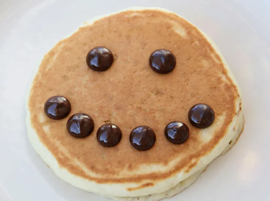 Download photo of vanilla pancakes decorated with cocoa in the shape of a smile 