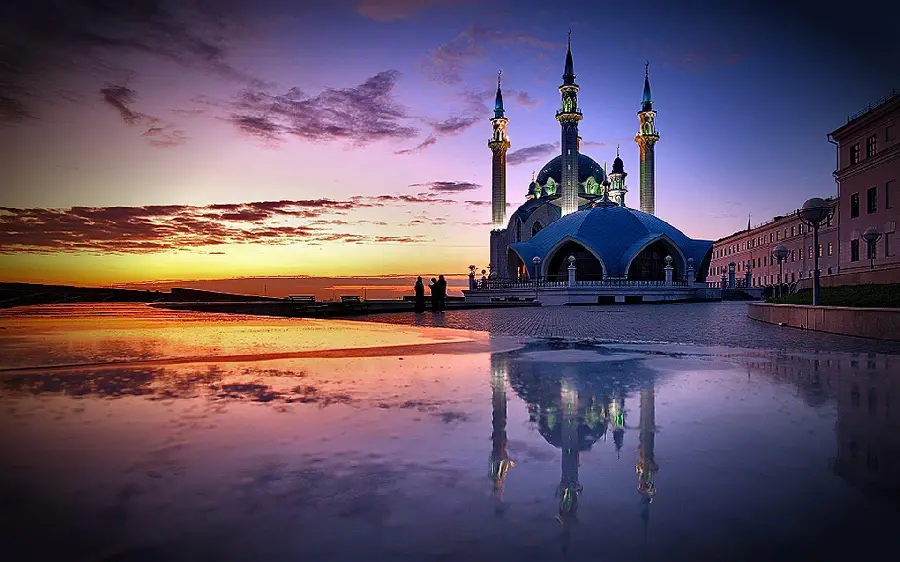 A very beautiful photo of a mosque by the water with a sunset 