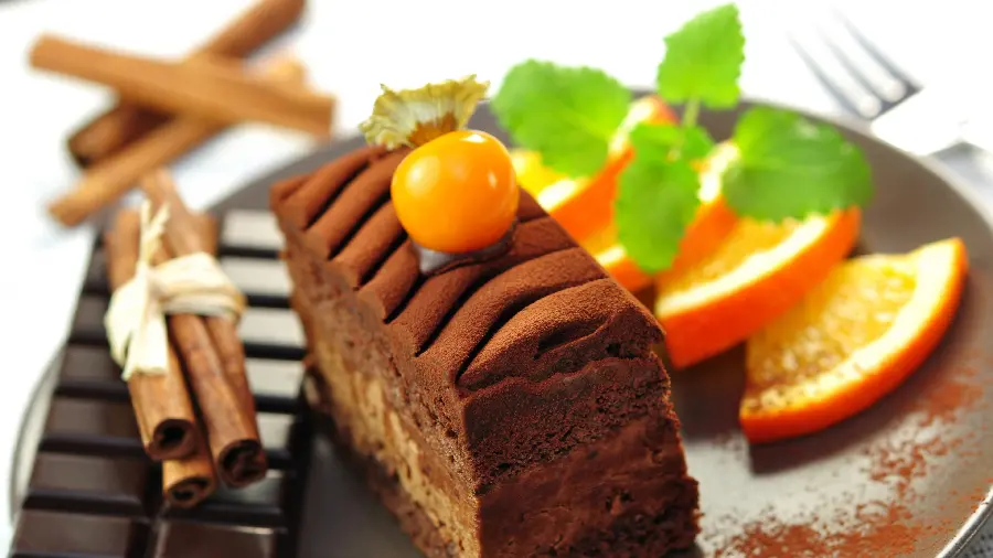 Stock image of a patterned cocoa cake with oranges and mint leaves