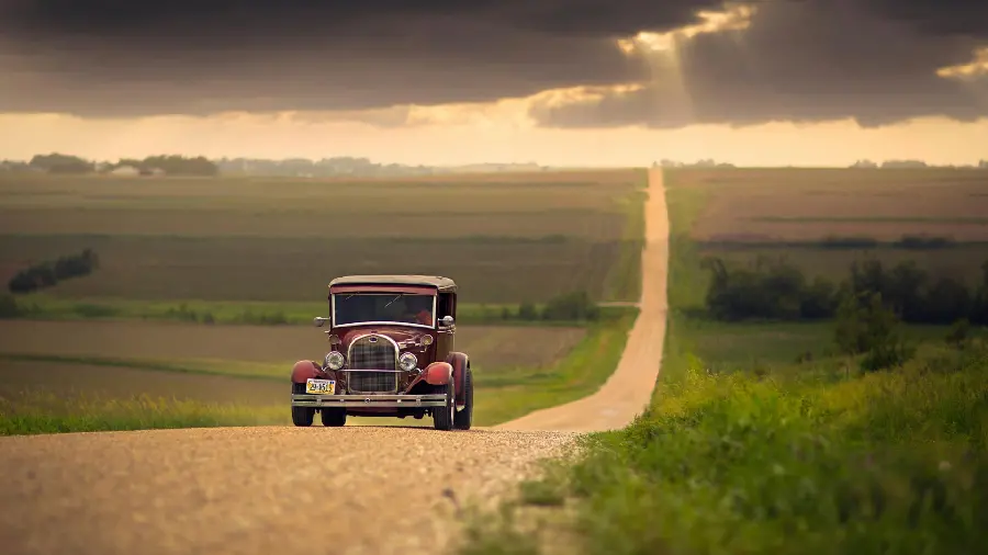 Attractive background of a red nostalgic car on a dirt road