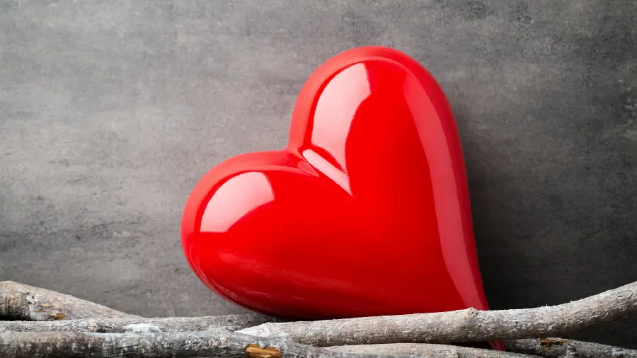 Romantic profile picture of a red shiny glass heart with a gray background