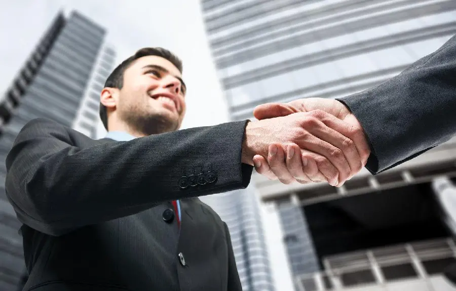 The most modern handshake photo next to a tall building in a suit