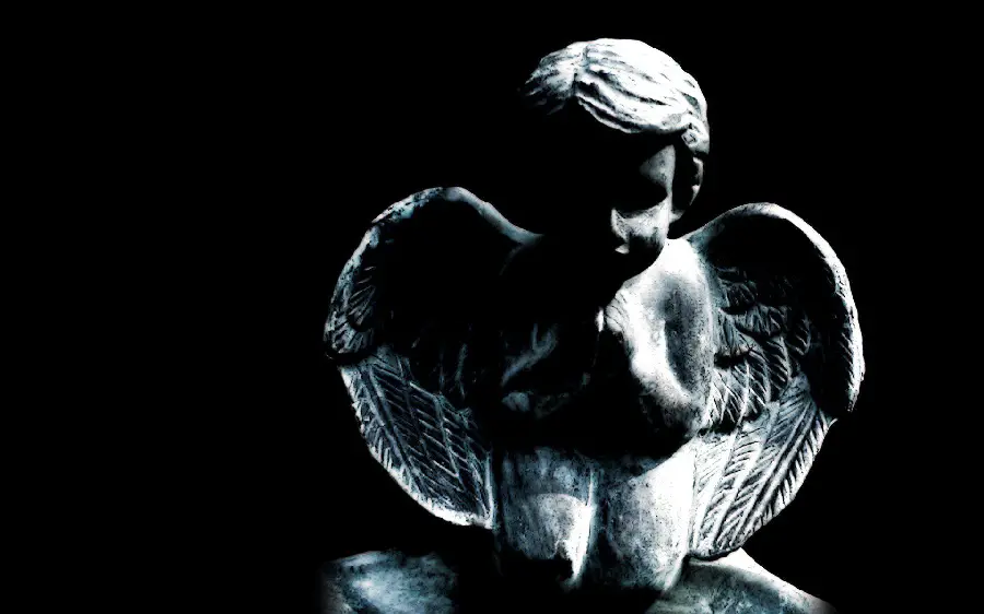 Black and white image of a kind angel statue with a black background 