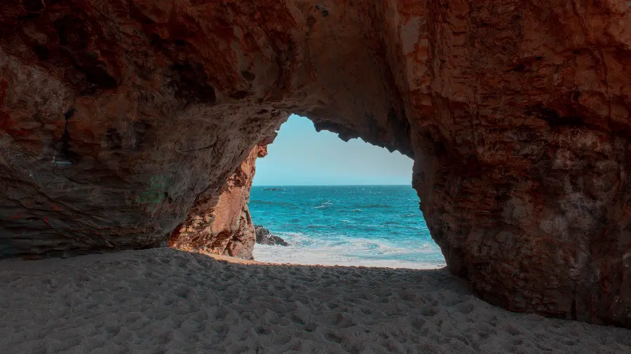 Download a refreshing attractive wallpaper from inside a cave on the beach
