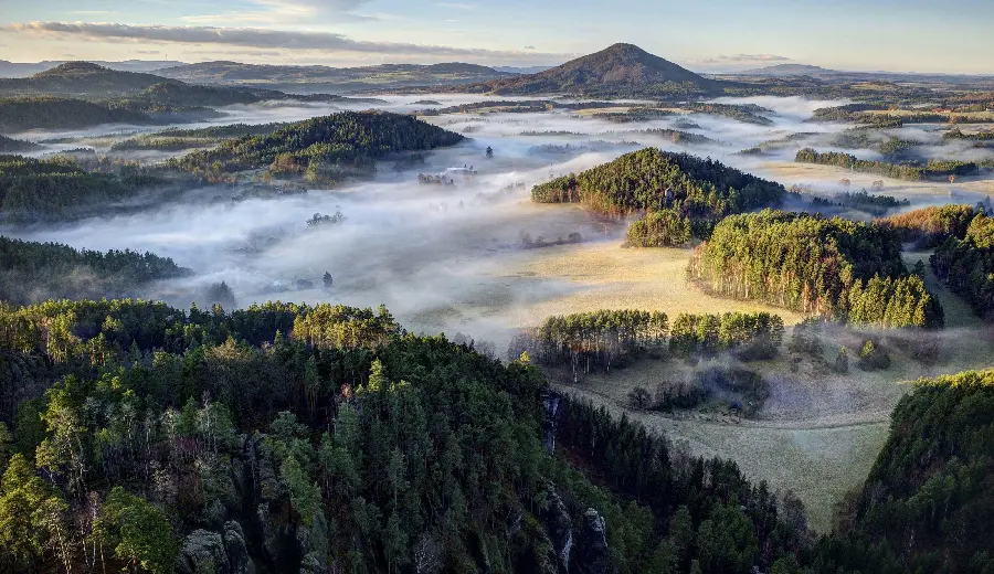 Lovely wallpaper of a dreamy view of green mountains above the clouds