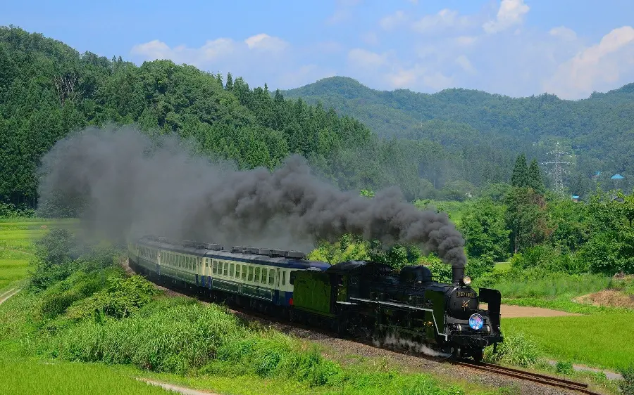 Wallpaper of an old black locomotive on rails in a spectacular nature for IOS