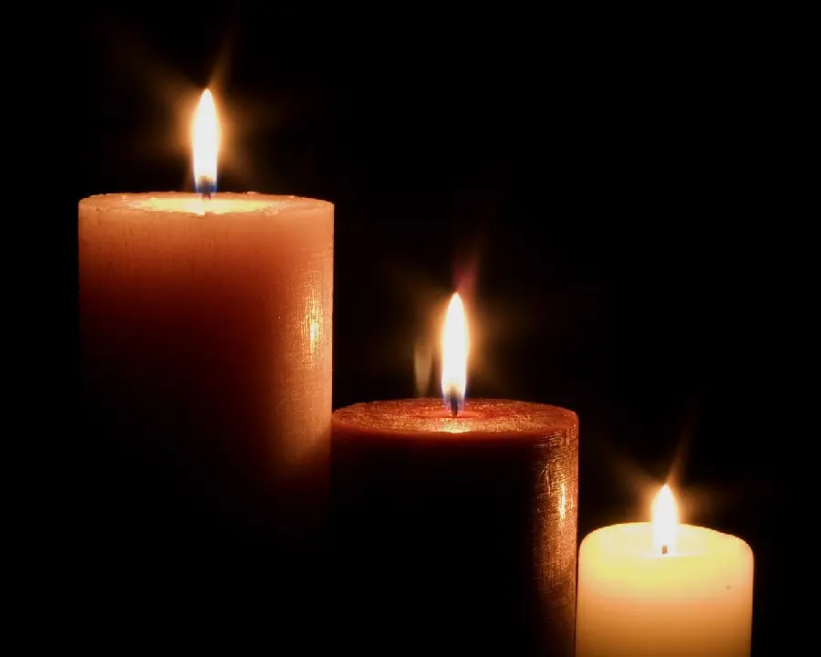 Photo of three lit candles on a black background for condolences to the bereaved