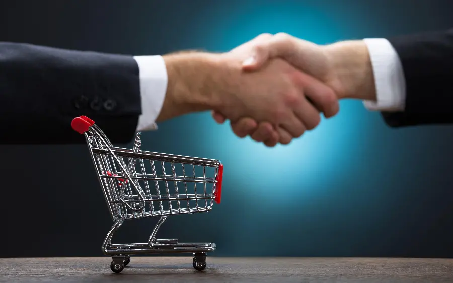 Stock photo of a gentleman and a lady shaking hands with a shopping cart background 
