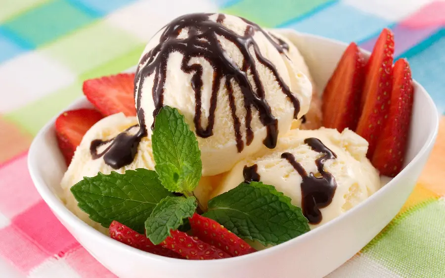Photo of luxury vanilla ice cream decorated with chocolate sauce and mint leaves and strawberries