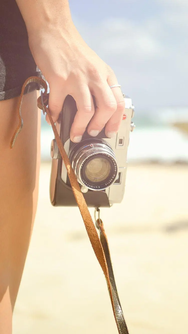 Free Image of Hand with Camera with Beach Background 