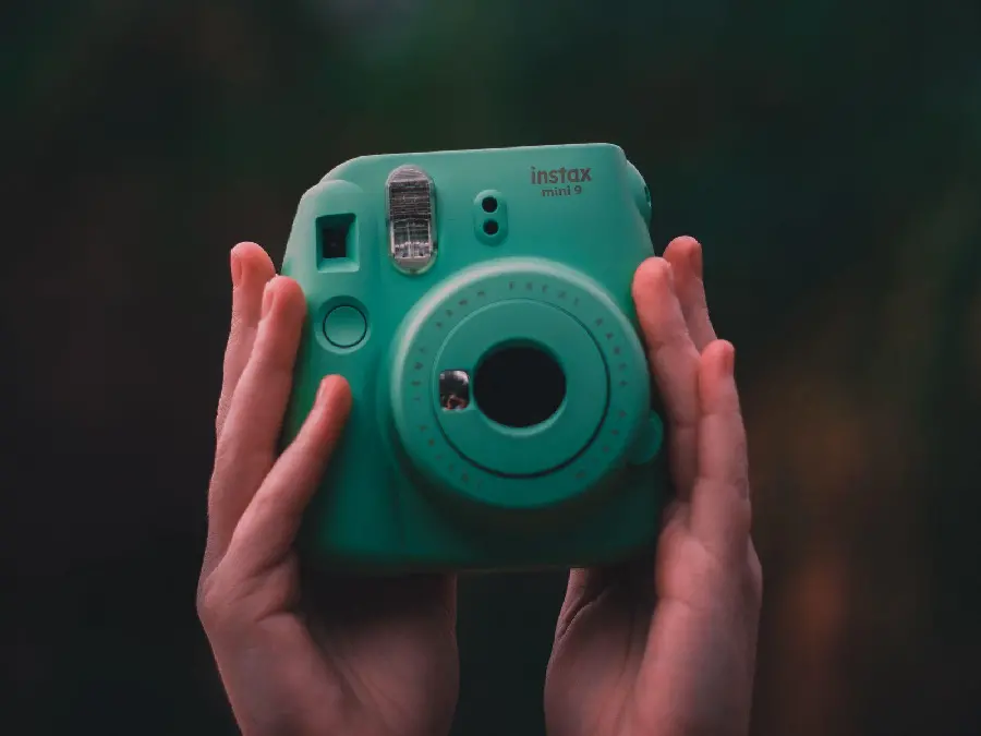 Image of a hand with a camera on a black background for backgrounds and profiles for girls
