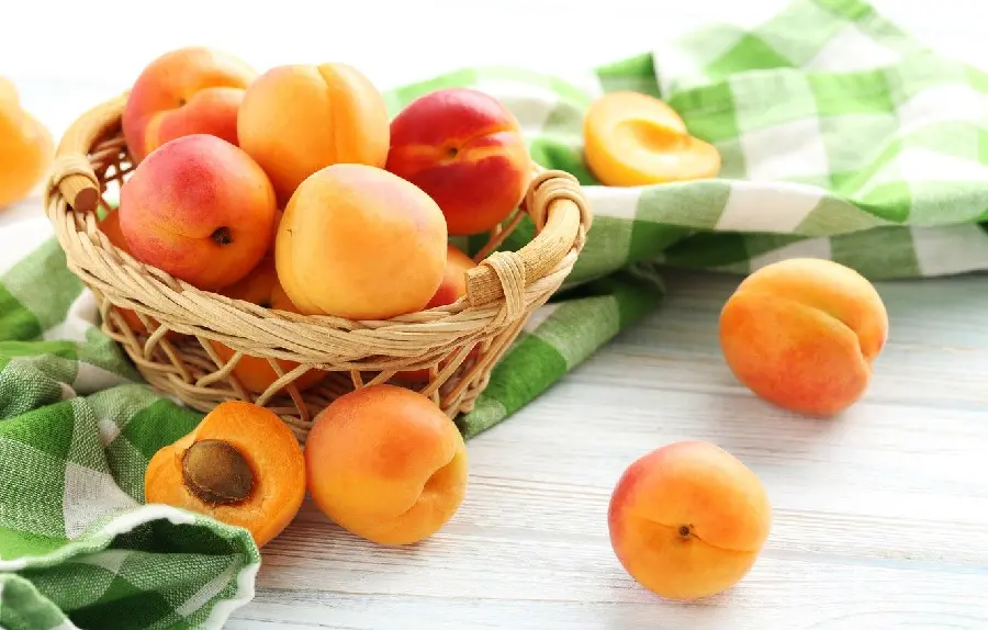 Beautiful wallpaper of ripe apricots in a wicker bowl on a green cloth