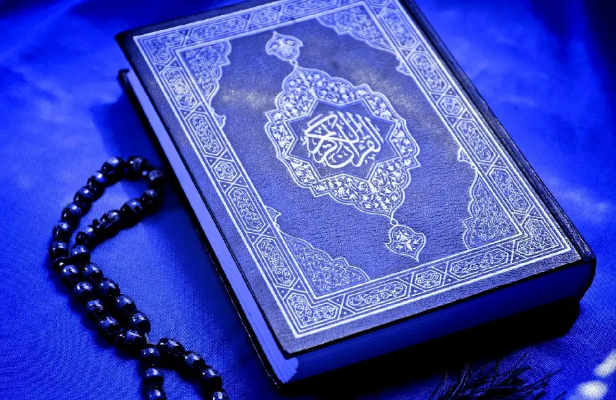 A charming and spectacular image of the blue Holy Quran with a rosary next to it 