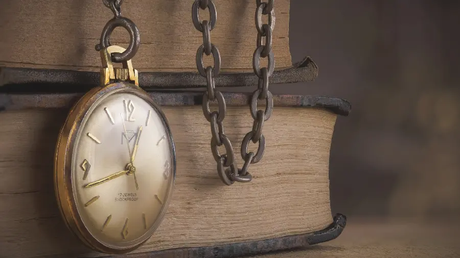 Profile photo of an old pocket watch with a metal chain on a book