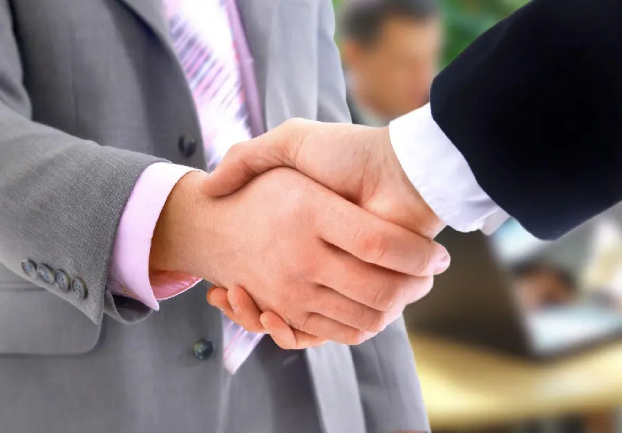 Download a simple and real stock photo of a handshake in the open air with a suit 